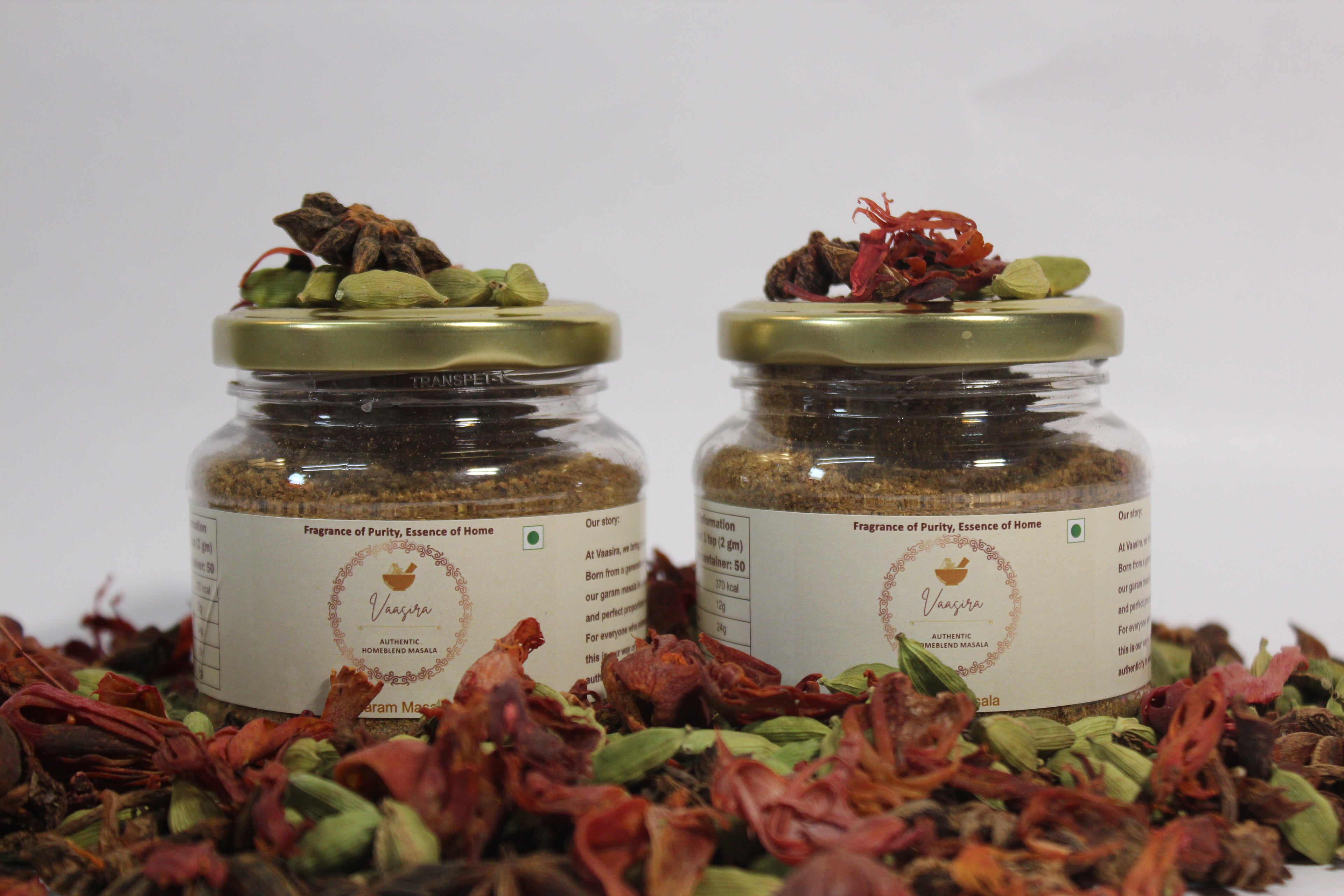 Home Blend Garam Masala Combo Pack jars filled with aromatic spices on a bed of cardamom and saffron.